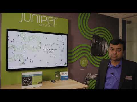 Still image of Manoj Leelanivas, COO at Juniper Networks standing next to a monitor at Mobile World Congress 2023. On the monitor it says “RAN Intelligent Controller.”